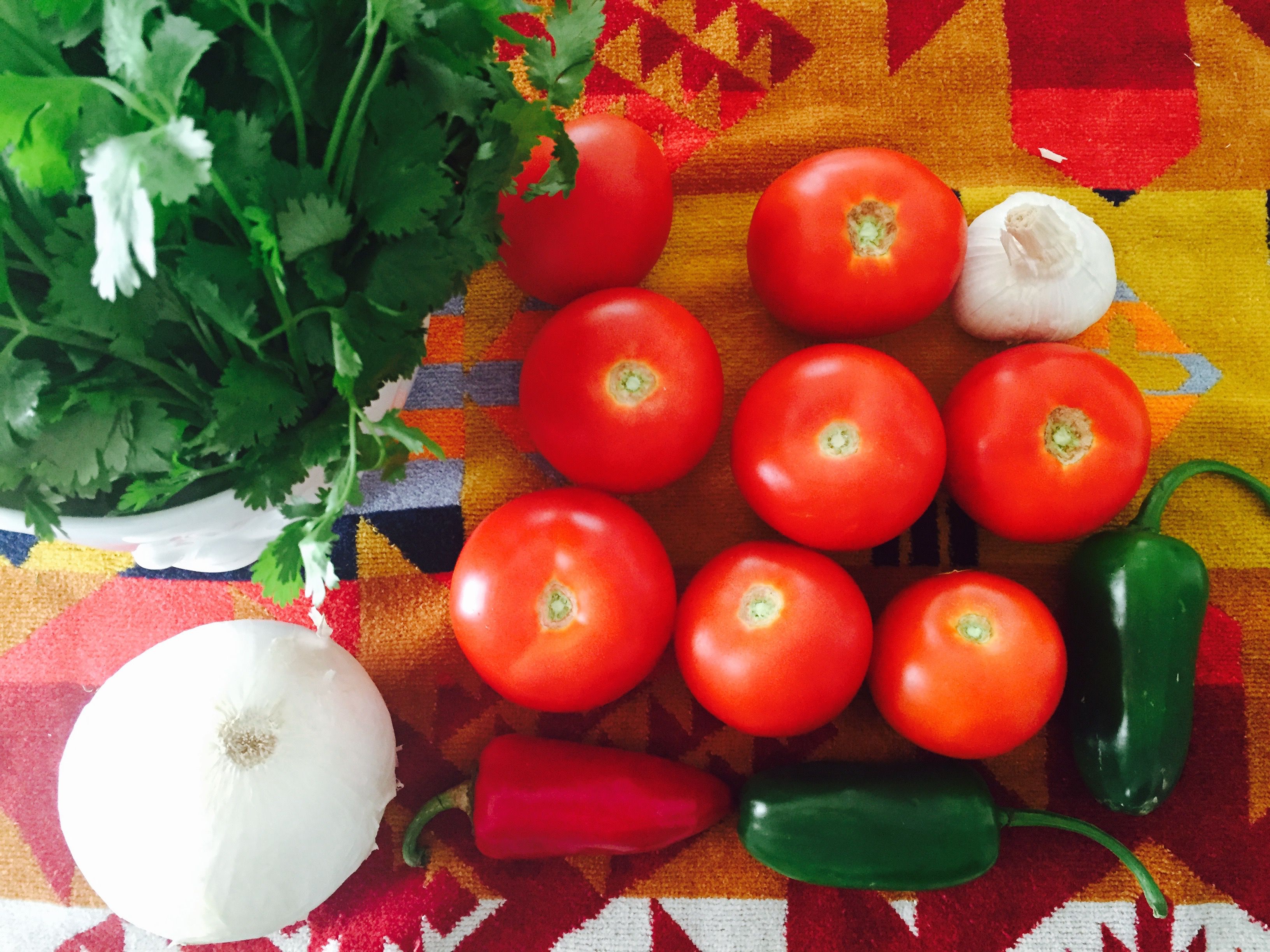  Zutaten 1kg frische Tomaten 2-3 Jalapeño-Chilischoten 1 rote Chilischote 4-6 Knoblauchzehen 1/2 weiße Zwiebel (die andere Hälfte vor dem Servieren würfeln) Zum Rösten des Gemüses 75ml Pflanzenöl 1 EL Salz Im Mixer hinzugeben Saft 1 Limette 1 EL Salz 1 EL Kreuzkümmel Vor dem Servieren hinzugeben 1/2 weiße Zwiebel, gewürfelt 1 handvoll frische Korianderblätter Zubereitung 1. Ofen auf 230C vorheizen. Das Gemüse und den Koriander waschen und trocknen. 2. Knoblauch und Zwiebel schälen. Zwiebel in der Mitte durchschneiden und eine Hälfte in vier Teile schneiden. Die andere Hälfte der Zwiebel fein würfeln (wird vor dem Servieren unter die Salsa gemischt). Die Korianderblätter zupfen und in einer Schüssel beiseite stellen. 3. Stielansätze und Kerngehäuse der Tomaten entfernen. Auch bei den Pfefferschoten den Stiel entfernen und alle Saatkerne entfernen. 4. In einer Schüssel die Tomaten und Pfefferschoten mit Pflanzenöl schwenken und mit Salz bestreuen. 5. Die Tomaten in eine ofenfeste Pfanne oder Auflaufform geben und die Knoblauchzehen ins Innere der Tomaten (wo Stielansätze und Kerngehäuse entfernt wurden) stopfen. Auf diese Weise verbrennt der Knoblauch nicht – alter Mexikanertrick! Ebenso die Pfefferschoten und Zwiebelscheiben in die Tomaten stopfen. 6. Jetzt wird’s heiß! Das Gemüse im Ofen bei 230C rund 30 Minuten rösten. Wenn die Haut der Pfefferschoten und Tomaten leichte Blasen aufweist, noch ein paar Minuten warten und aus dem Ofen nehmen. Ein paar angeschwärzte Stellen sind auch okay, je nachdem wie sehr „durchgeröstet“ der Geschmack sein soll. 7. Das Gemüse aus dem Ofen nehmen und eine halbe Stunde abkühlen lassen. 8. Jetzt das geröstete Gemüse und ausgekochten Saft in einen Mixer gießen. Den Saft der Limette und Kreuzkümmel hinzugeben. Brumm! Brumm! Einige Male durchmixen, bis die Salsa den gewünschten Flüssigkeitsgrad erreicht hat. 9. Zum Servieren die Salsa portionsweise in Schalen gießen – wir hätten da ein paar nette im Shop – und den Koriander sowie die gehackten Zwiebeln hinzugeben. (Soll die Salsa für den späteren Verzehr gelagert werden, besser erst direkt vor dem Servieren die Zwiebeln und Koriander beimischen, „ohne“ hält sich die Salsa länger.) 10. Fehlen nur noch Chips und ein paar Freunde – und die Salsa-Party kann losgehen! Natürlich könnt ihr die Art und Menge der Pfefferschoten frei variieren und dementsprechend mehr – oder weniger – Schärfe ins Spiel bringen. Gleiches gilt für den Knobi. Manche Leute grillen ihre Zutaten gern auf dem Grill, was für eine rauchige Geschmacksnote sorgt. Andere mischen gegrillte Ananas oder Mango in ihre Salsa. Alles ist erlaubt und die Variationsmöglichkeiten sind endlos. Ach so, eine Sache noch: Nach dem Schneiden und Zubereiten der Pfefferschoten bitte gründlich die Hände waschen, bevor man ins Gesicht greift oder die Augen reibt und dergleichen. Sonst wird’s brenzlig. Wir wünschen guten Appetit und jede Menge gute Salsa-Laune mit unserem Sommer-Rezept! Eure Freunde von TASSEN. 